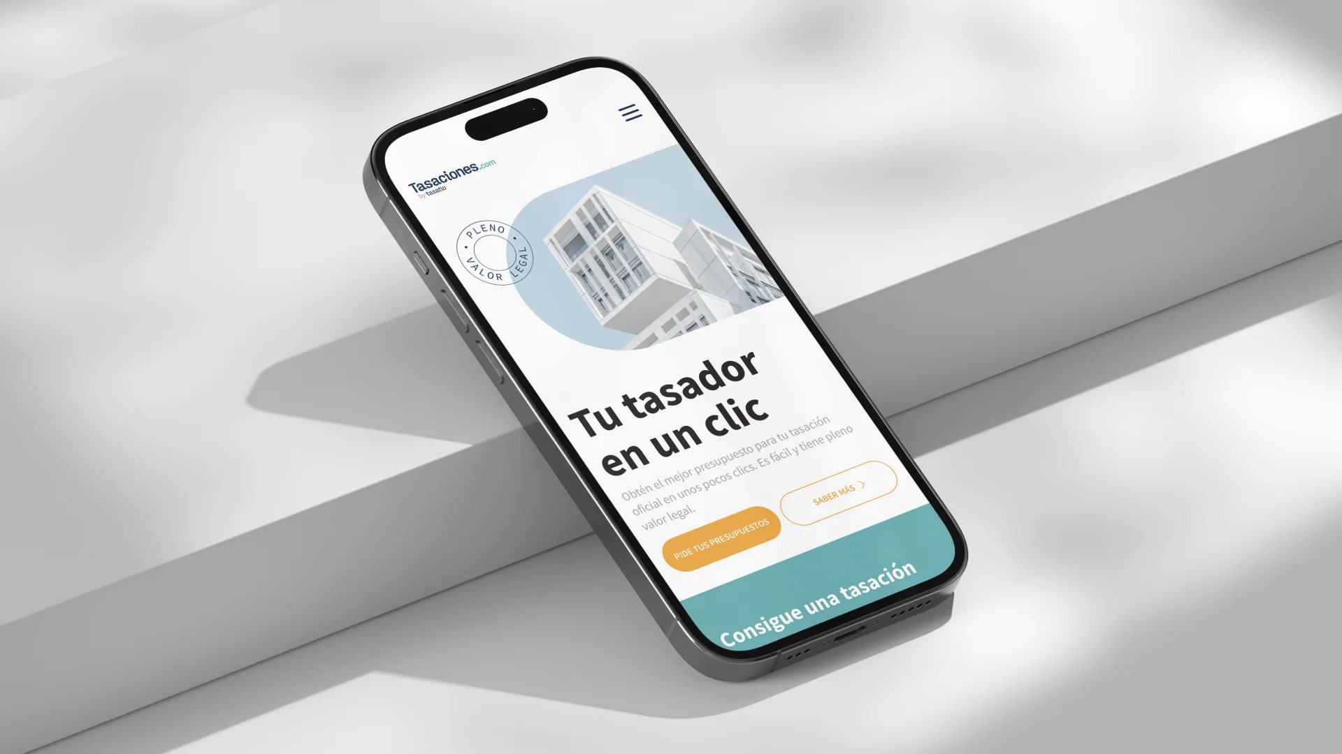 Pantalla de inicio de Tasaciones.com dentro de un dispositivo móvil, mostrando el eslogan Tu tasador en un clic junto con botones para que el usuario se registre o inicie el proceso de tasación.