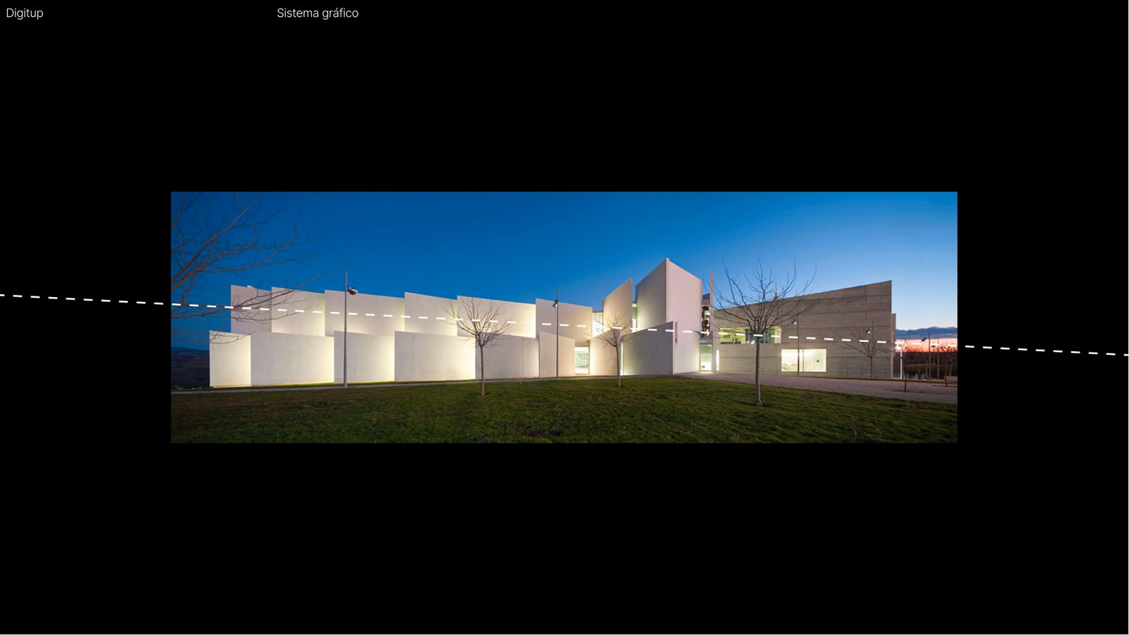 Edificio moderno de la Universidad San Jorge iluminado al anochecer.